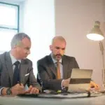 portrait successful businessmen office two serious man suits working with computer table making decisions developing strategy business growth business growth finance concept