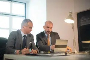 portrait successful businessmen office two serious man suits working with computer table making decisions developing strategy business growth business growth finance concept