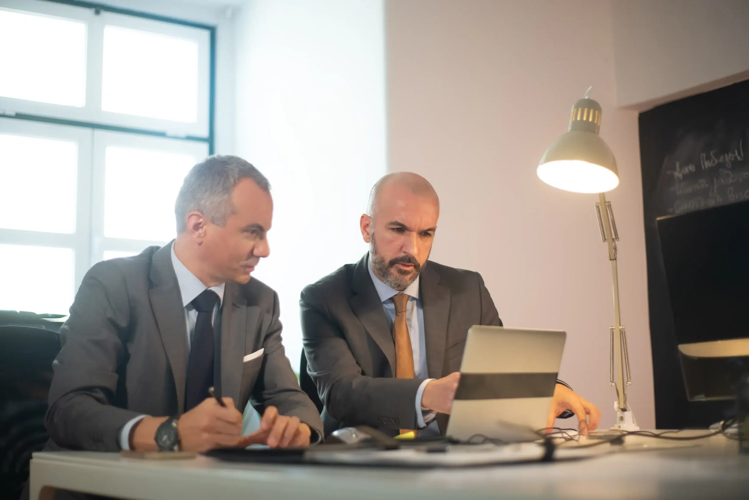 portrait successful businessmen office two serious man suits working with computer table making decisions developing strategy business growth business growth finance concept scaled