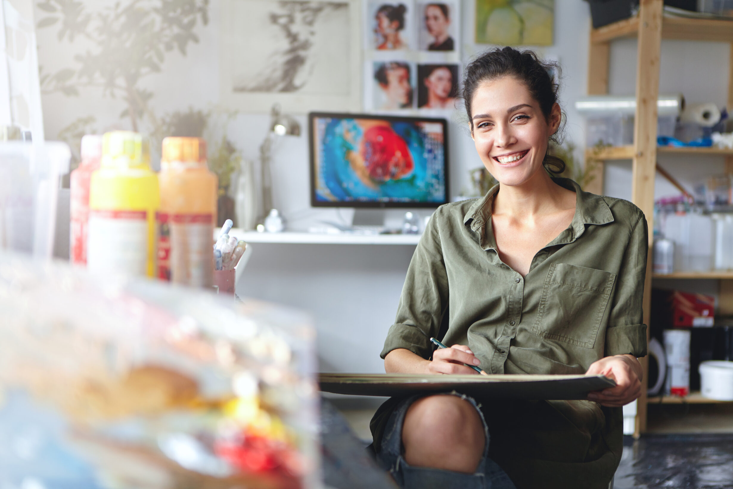 smiling female artist wearing casual clothes sitting her cabinet with sketches colorful paint having happy expression while being glad create beautiful picture painter working workshop scaled